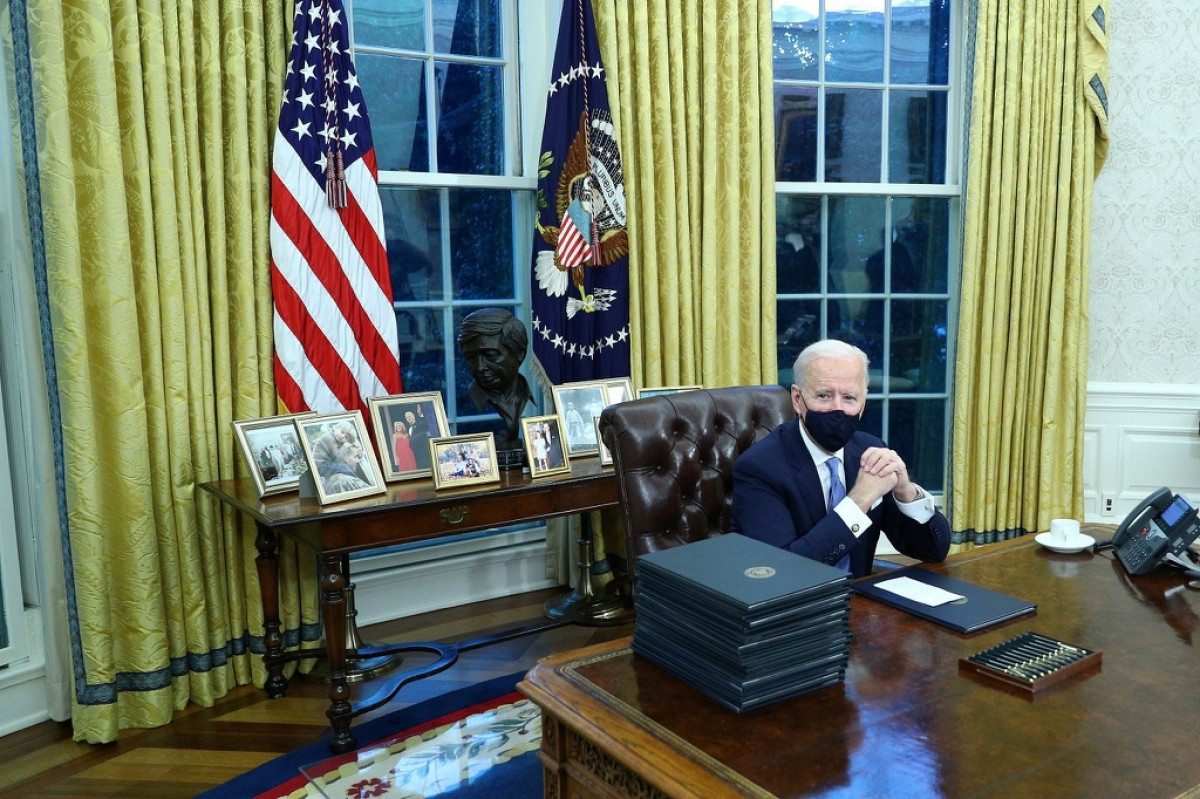 Ông Biden ngồi trên một chiếc ghế da màu nâu sẫm, phía sau là các bức ảnh gia đình. Ảnh: Washington Post.