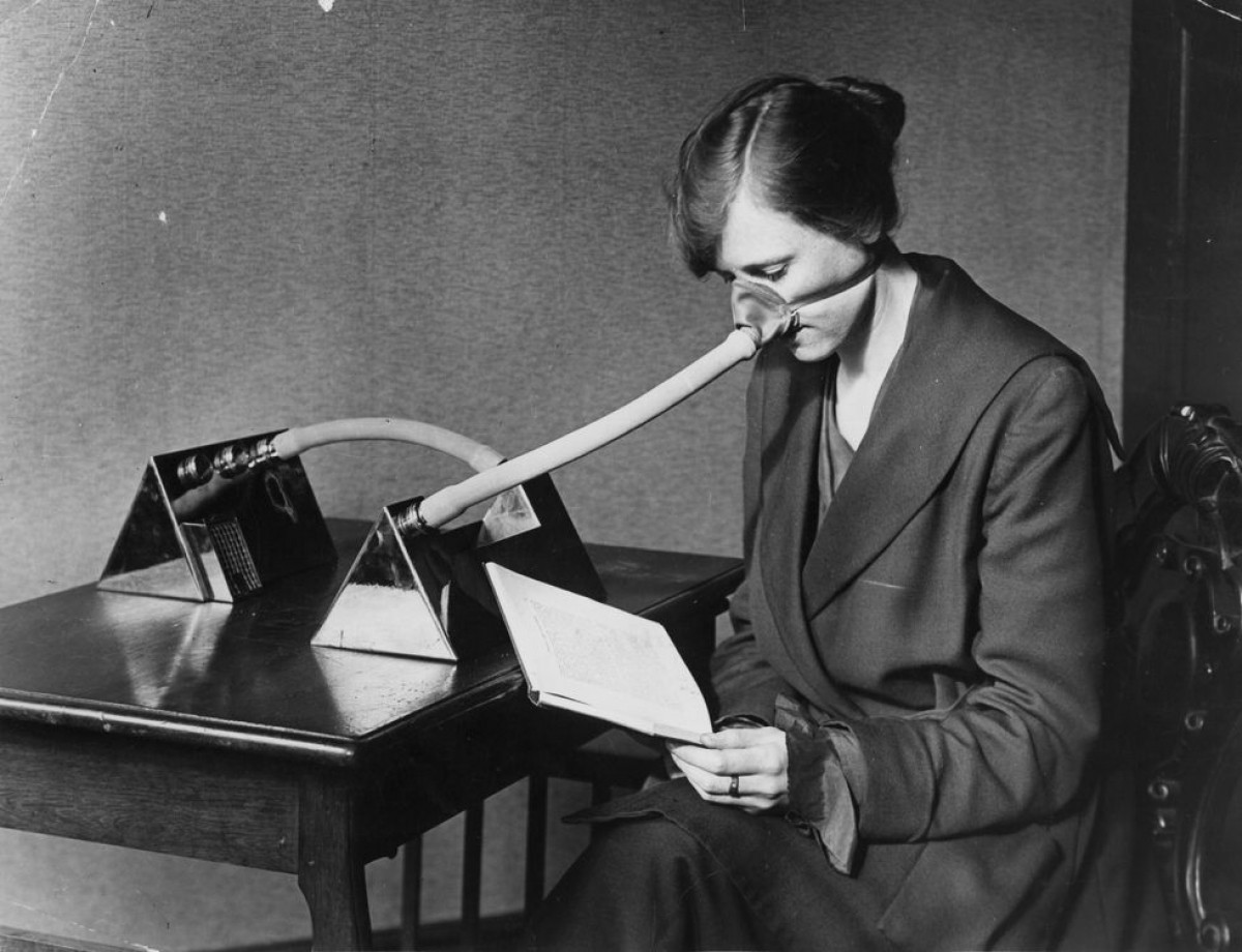 Mặt nạ phòng cúm. Một người phụ nữ đang đọc sách trên bàn làm việc trong khi đeo 