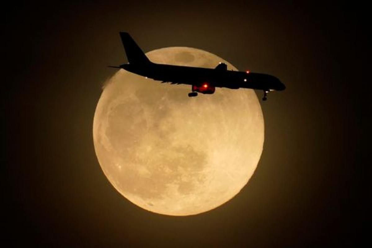Một máy bay bay qua siêu trăng hồng ở Louisville, bang Kentucky (Mỹ).