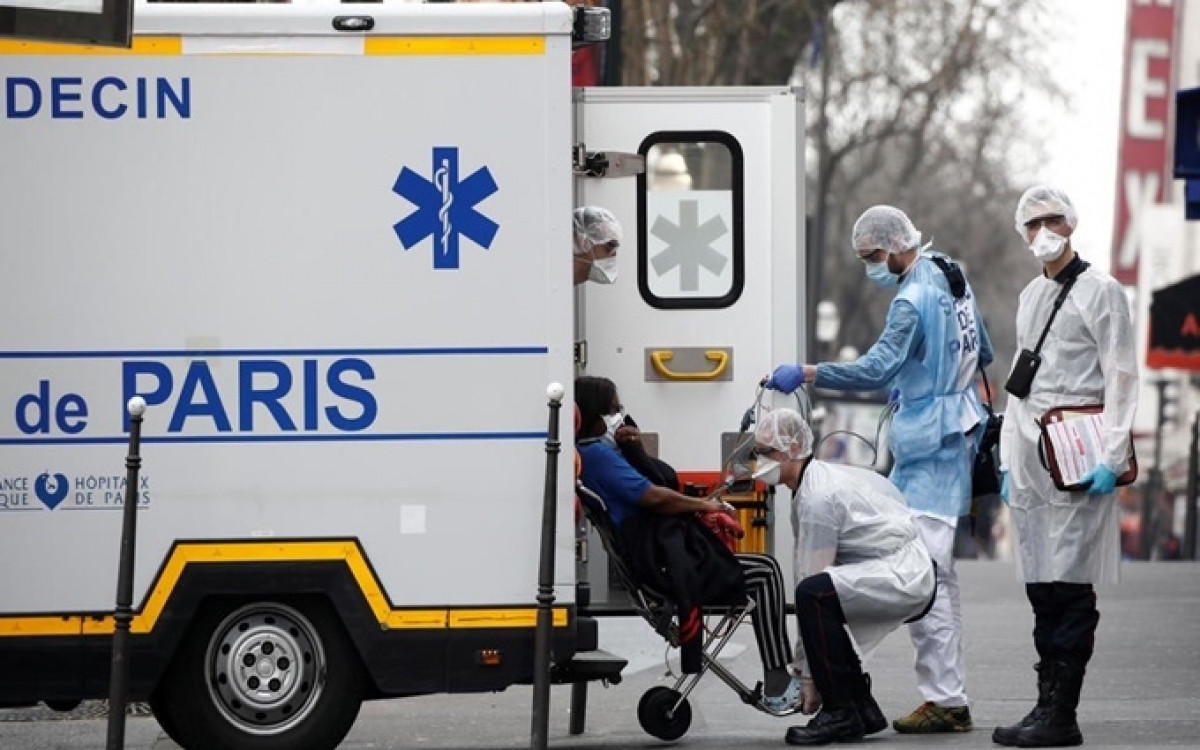 Nhân viên cấp cứu di chuyển bệnh nhân bị nghi mắc Covid-19 từ nhà đến bệnh viện ở Paris, Pháp, ngày 20/3. (Ảnh: Reuters)
