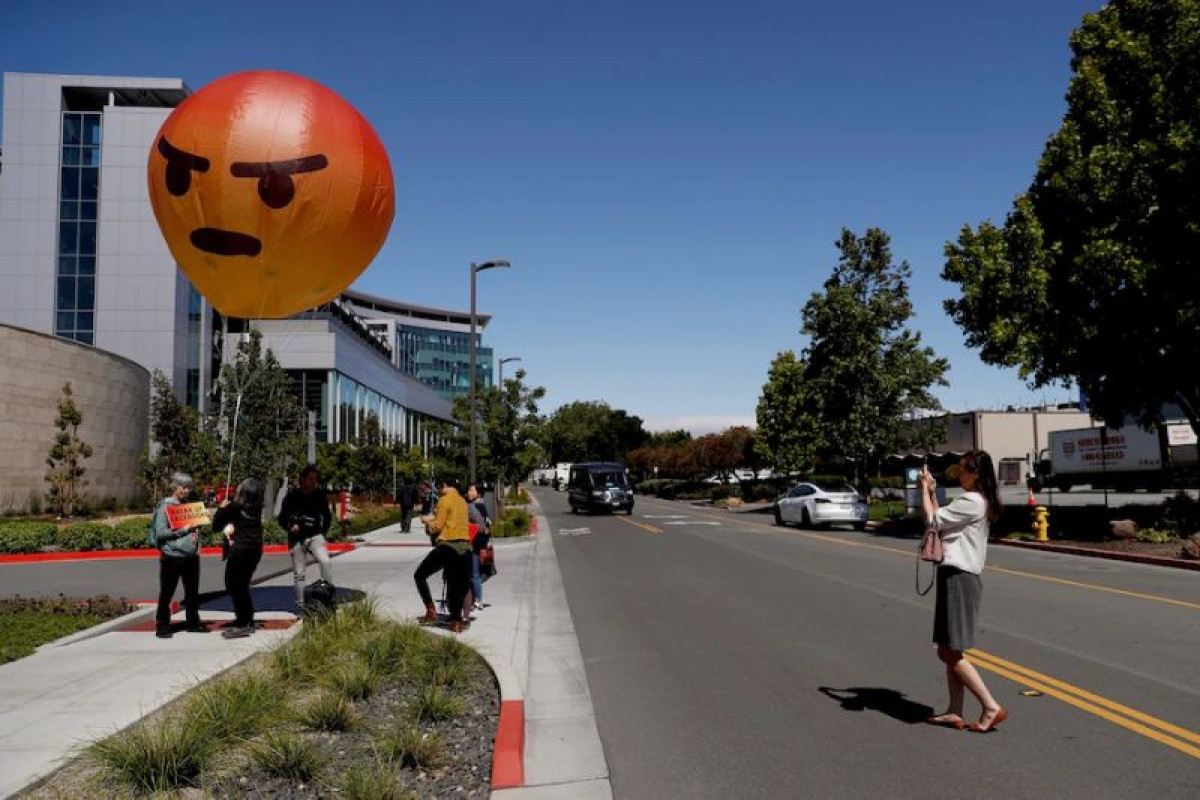 Người biểu tình Facebook cầm bong bóng có hình emoji phẫn nộ.