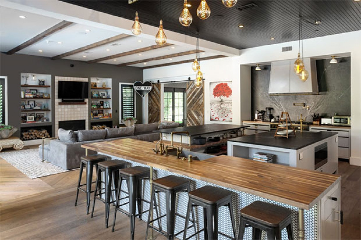 Phòng khách và khu vực bếp được thiết kế theo không gian mở, rộng rãi. Sự kết hợp giữa bảng màu xám lạnh và gỗ ấm là phong cách nội thất chủ đạo của toàn bộ ngôi nhà.