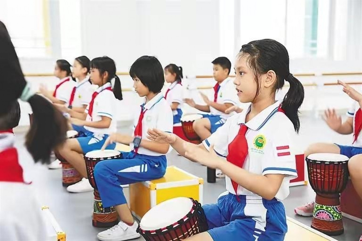 Học sinh một trường tiểu học ở thành phố Hải Khẩu, tỉnh Hải Nam đang học đánh trống châu Phi. Ảnh: Nhật báo Hải Nam