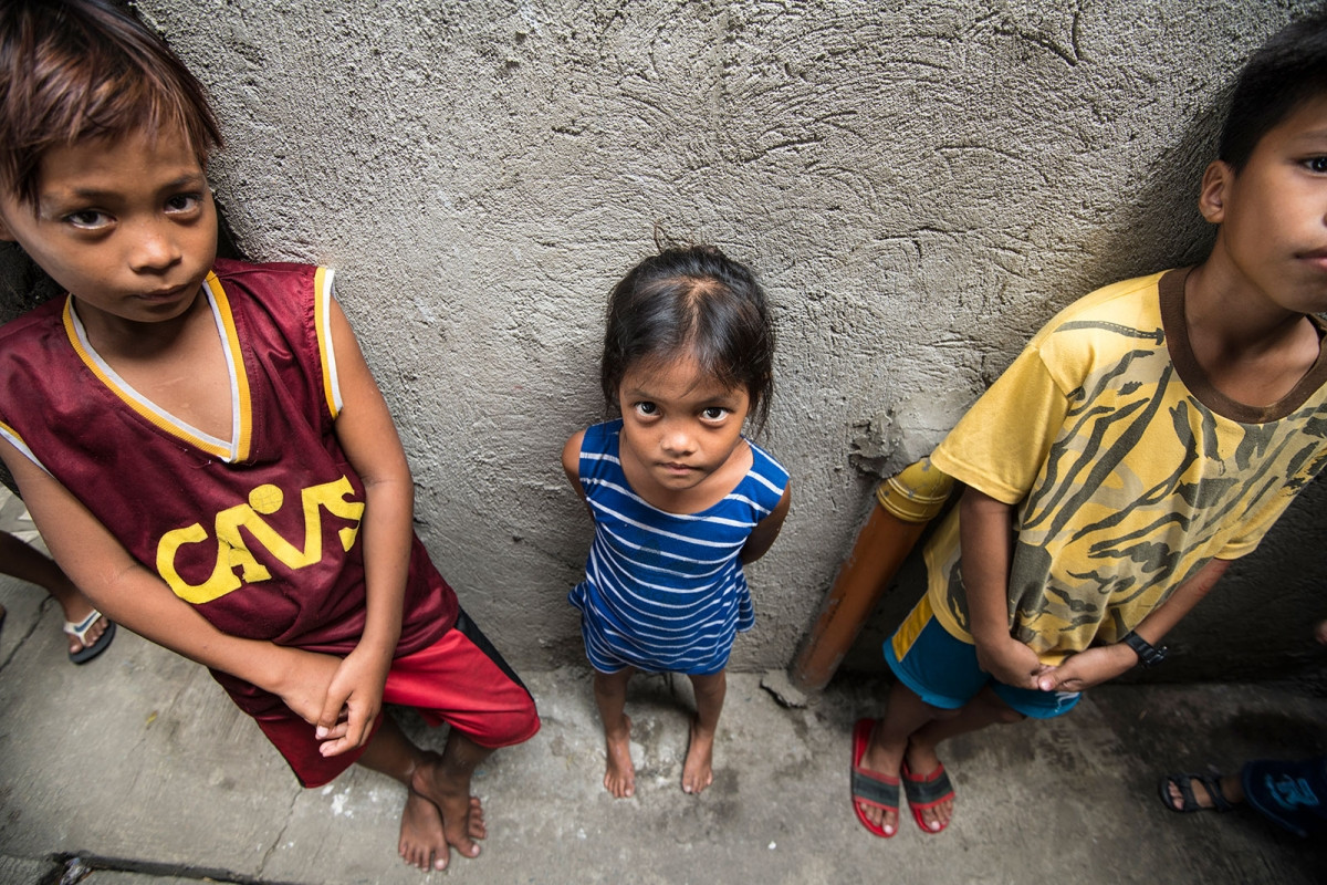 Một em nhỏ Philippines bị chứng thấp còi đứng giữa hai bạn cùng tuổi. Ảnh: EPA-EFE