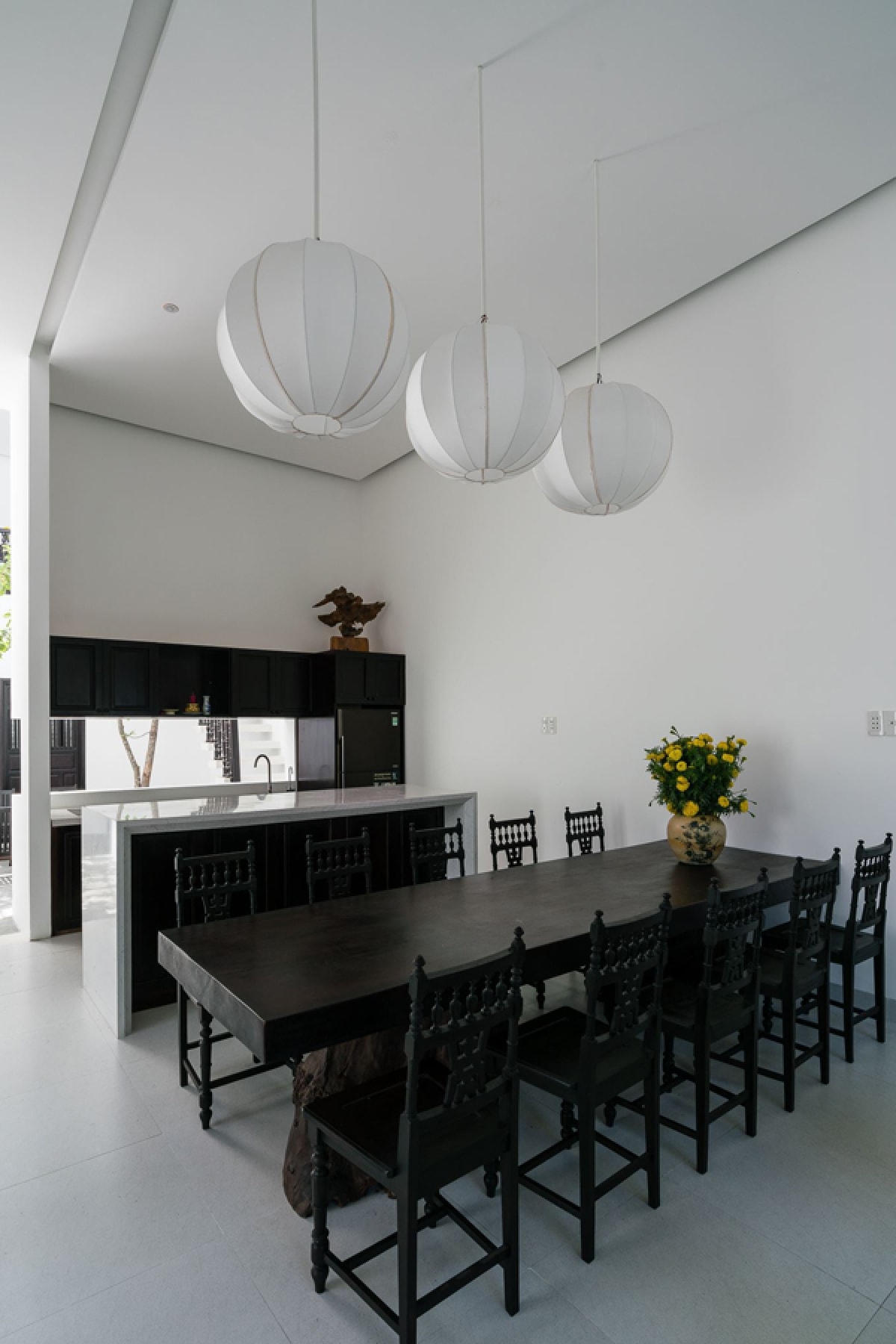 Tủ bếp gọn gàng, ngăn cách với bàn ăn bởi một quầy bar. Bộ bàn ăn dài có thể sử dụng linh hoạt và hữu dụng khi đông người.