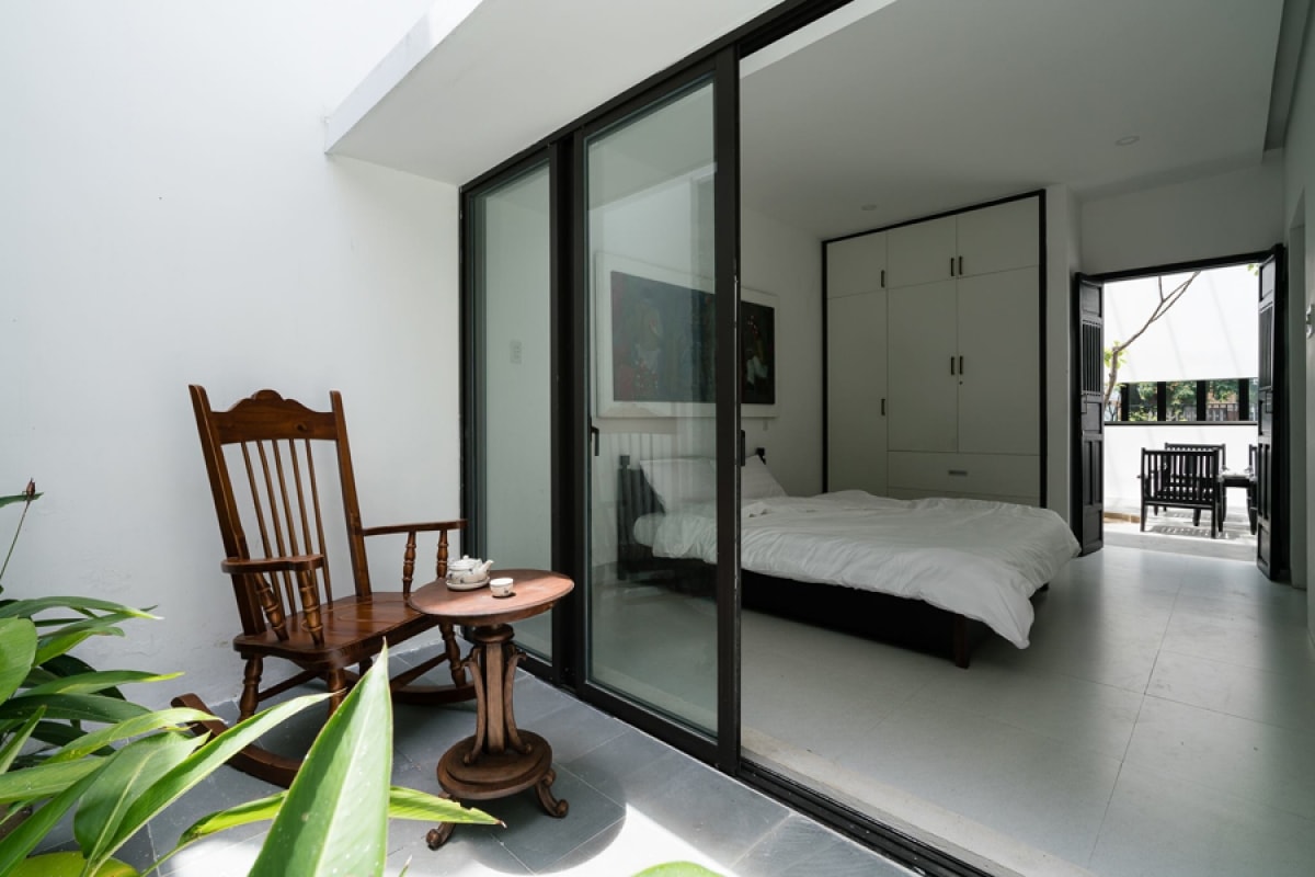 Phòng ngủ ở tầng trệt mở ra khoảng sân sau. Với vật liệu mới là vách kính tấm lớn, không gian được mở rộng, mang dấu ấn kiến trúc hiện đại.