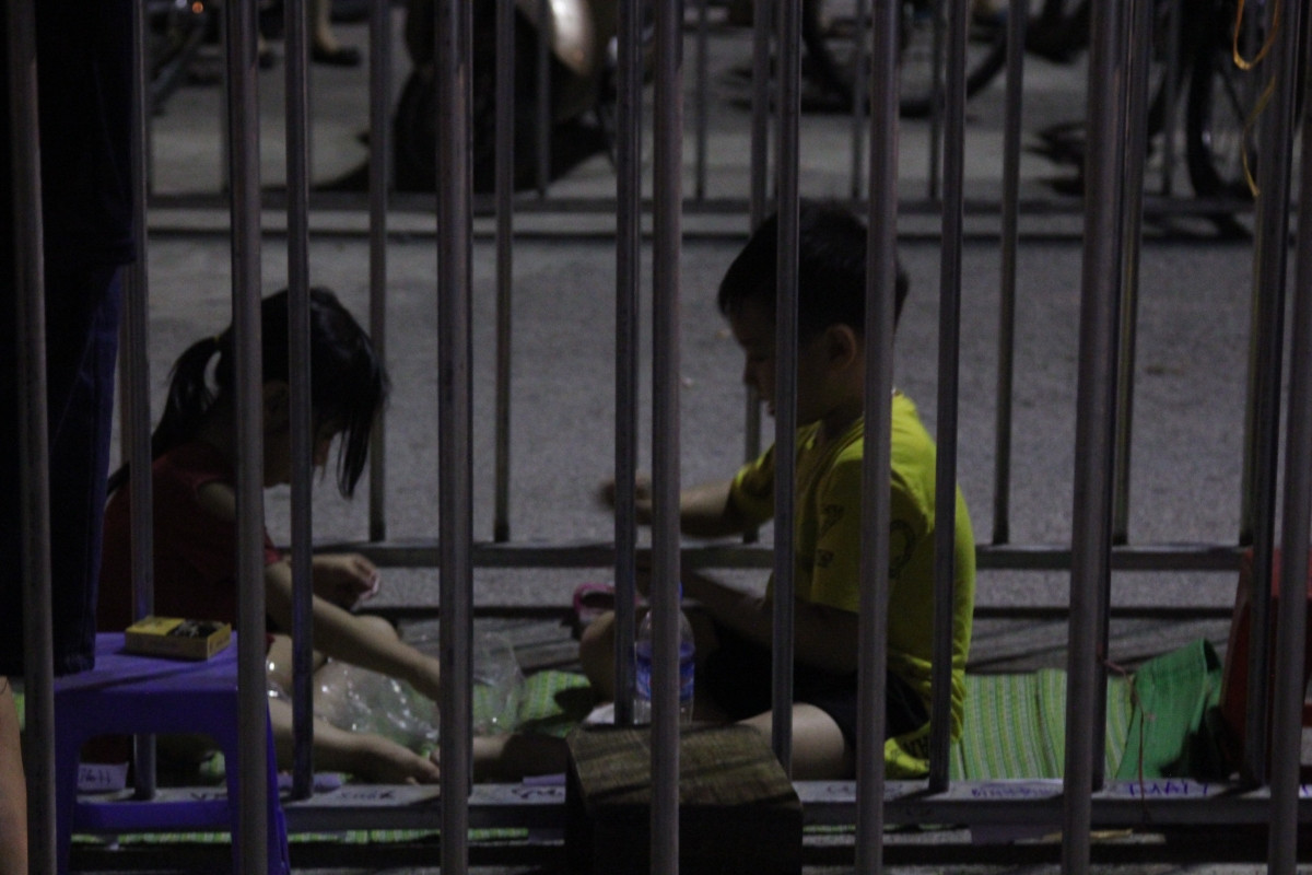 Nhiều gia đình đem theo trẻ nhỏ, mang trải chiếu để ăn tối, sinh hoạt ngay trước cổng sân.