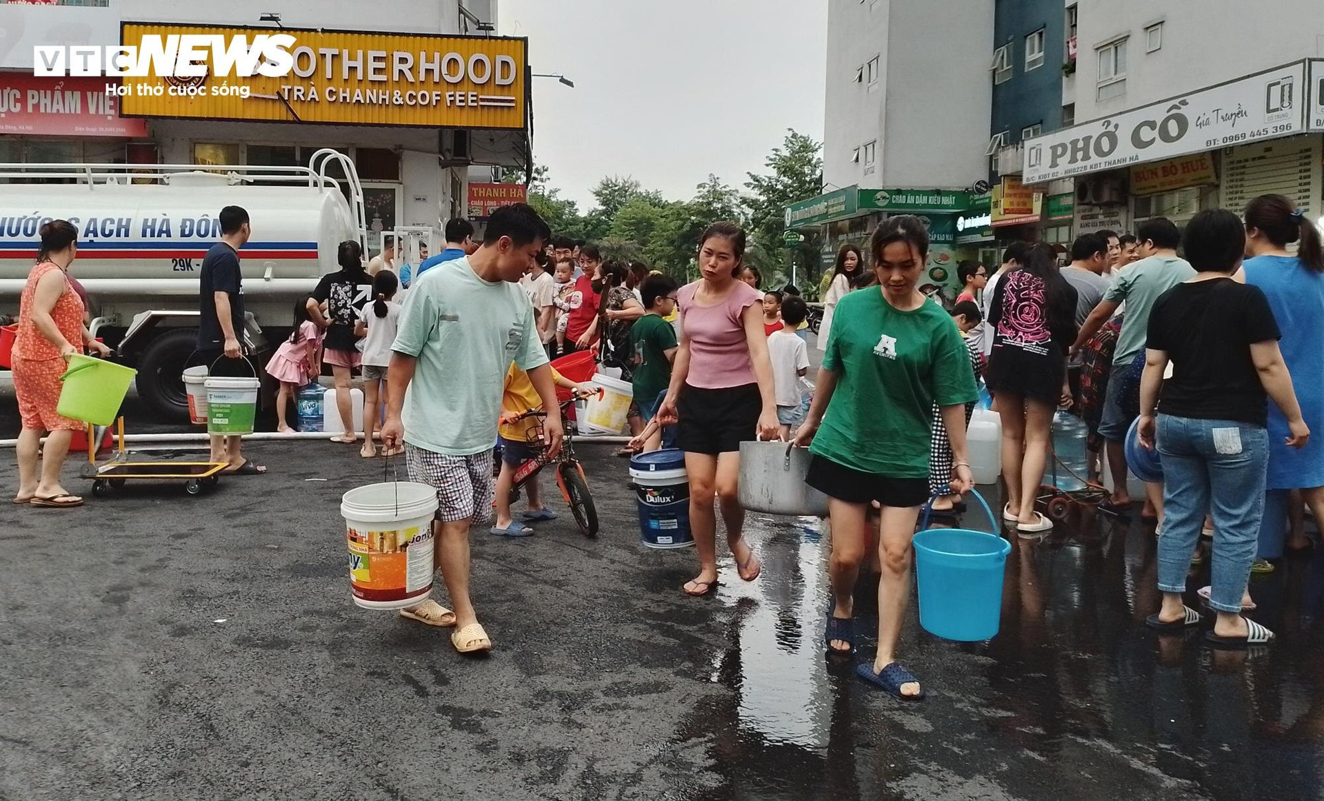 Hàng trăm cư dân Khu đô thị Thanh Hà, trong đó có cả người lớn, trẻ nhỏ cầm can loại 5 lít, thùng, xô, chậu… xuống sảnh chung của toà nhà, xếp hàng chờ đợi xe bồn chuyên dụng mang nước sạch đến.