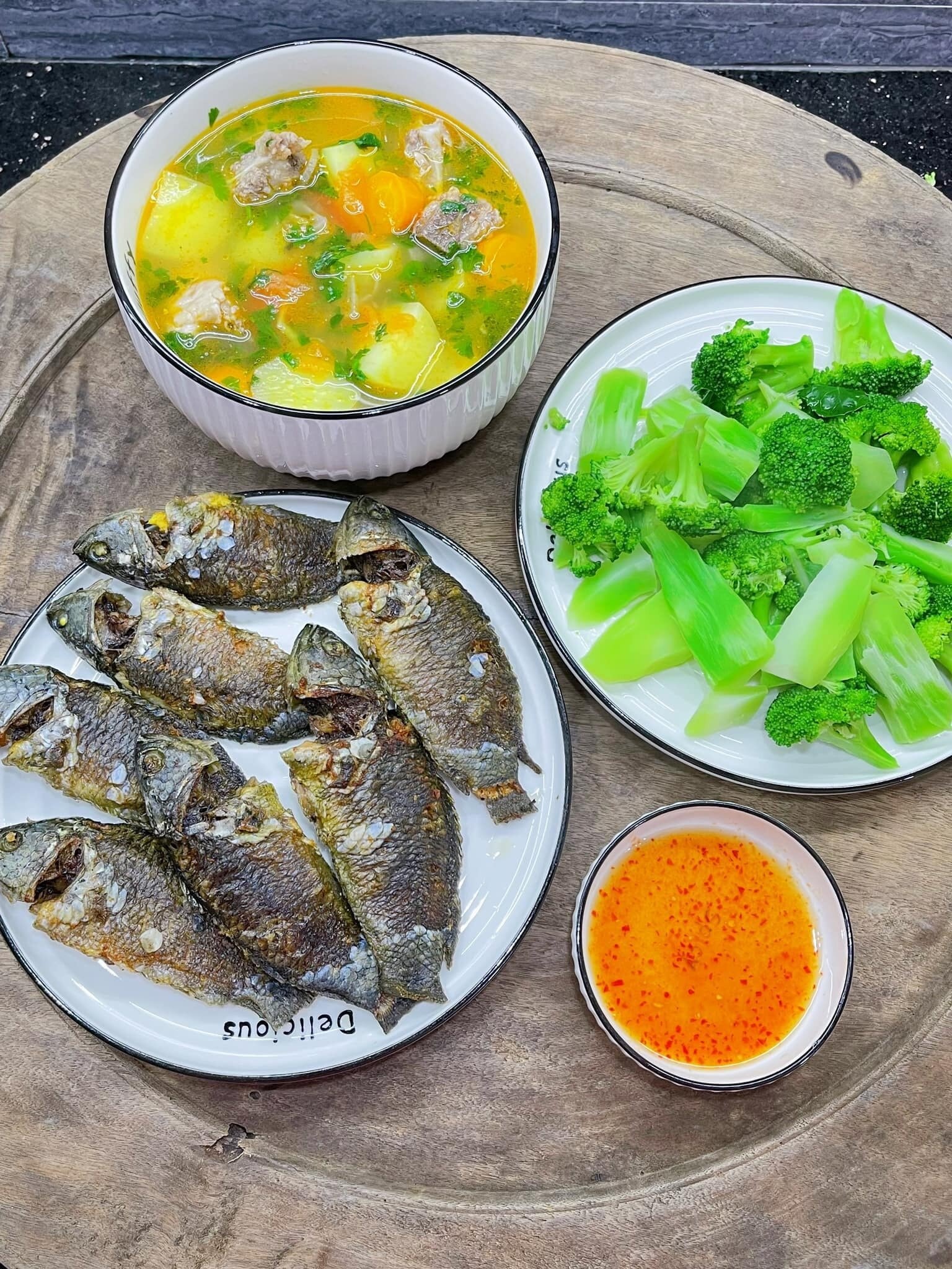 Canh xương nấu khoai tây cà rốt, súp lơ xanh luộc và cá rô rán.