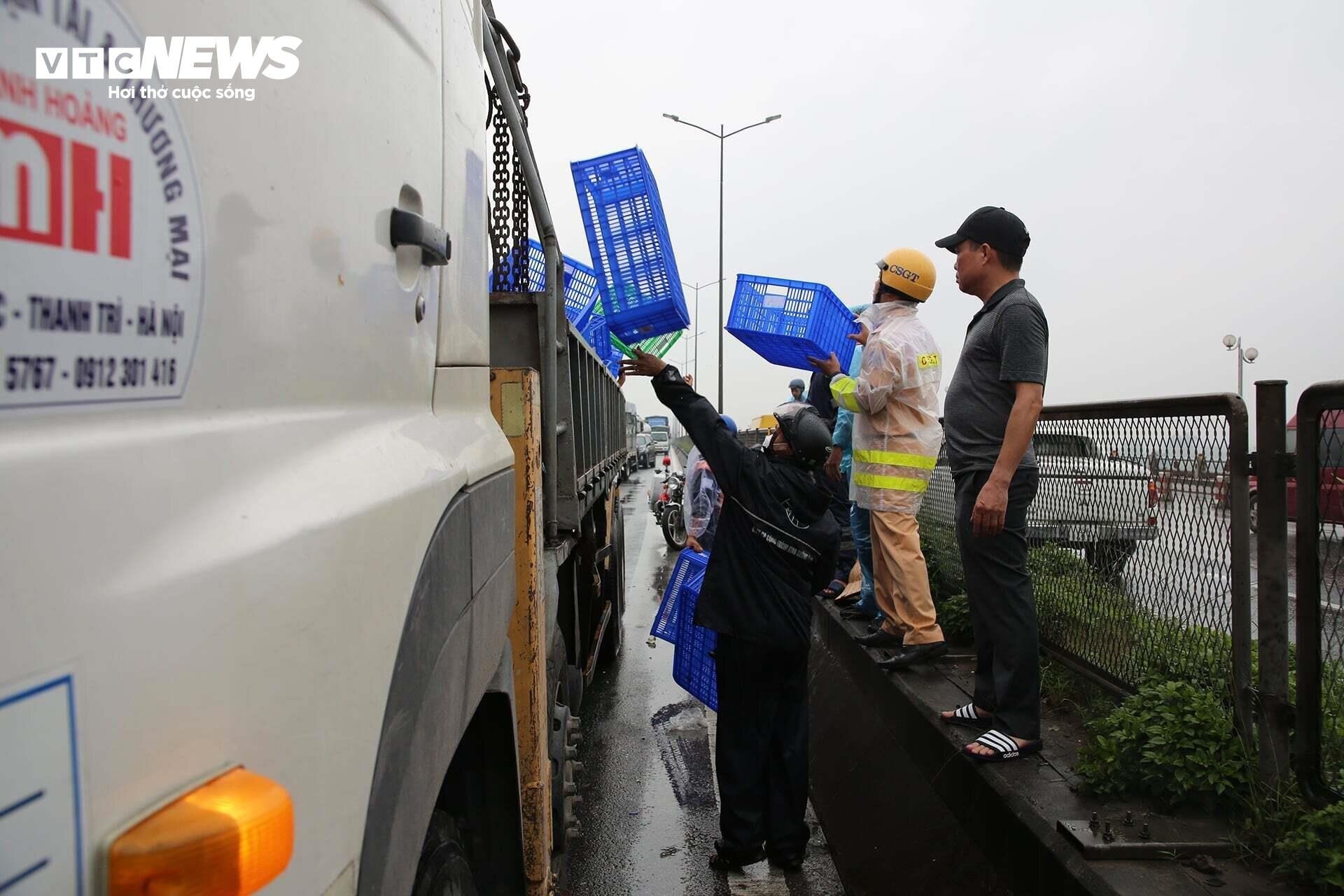 Lực lượng CSGT và người dân hỗ trợ tài xế thu gom hàng hoá, dọn dẹp mảnh vỡ vương vãi trên mặt cầu.