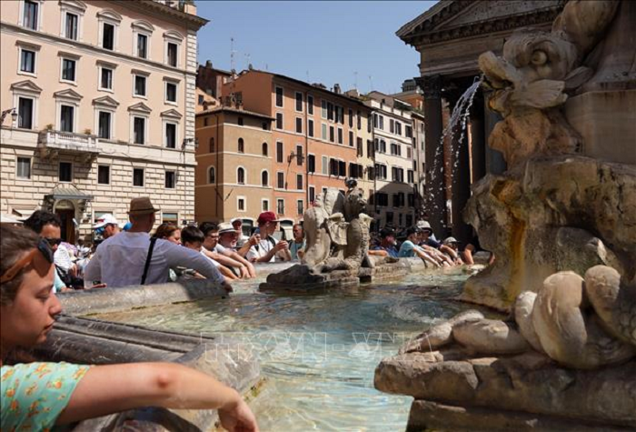 Khách du lịch tránh nóng bên đài phun nước tại Rome, Italy, ngày 18/7/2023. (Ảnh: THX/TTXVN)