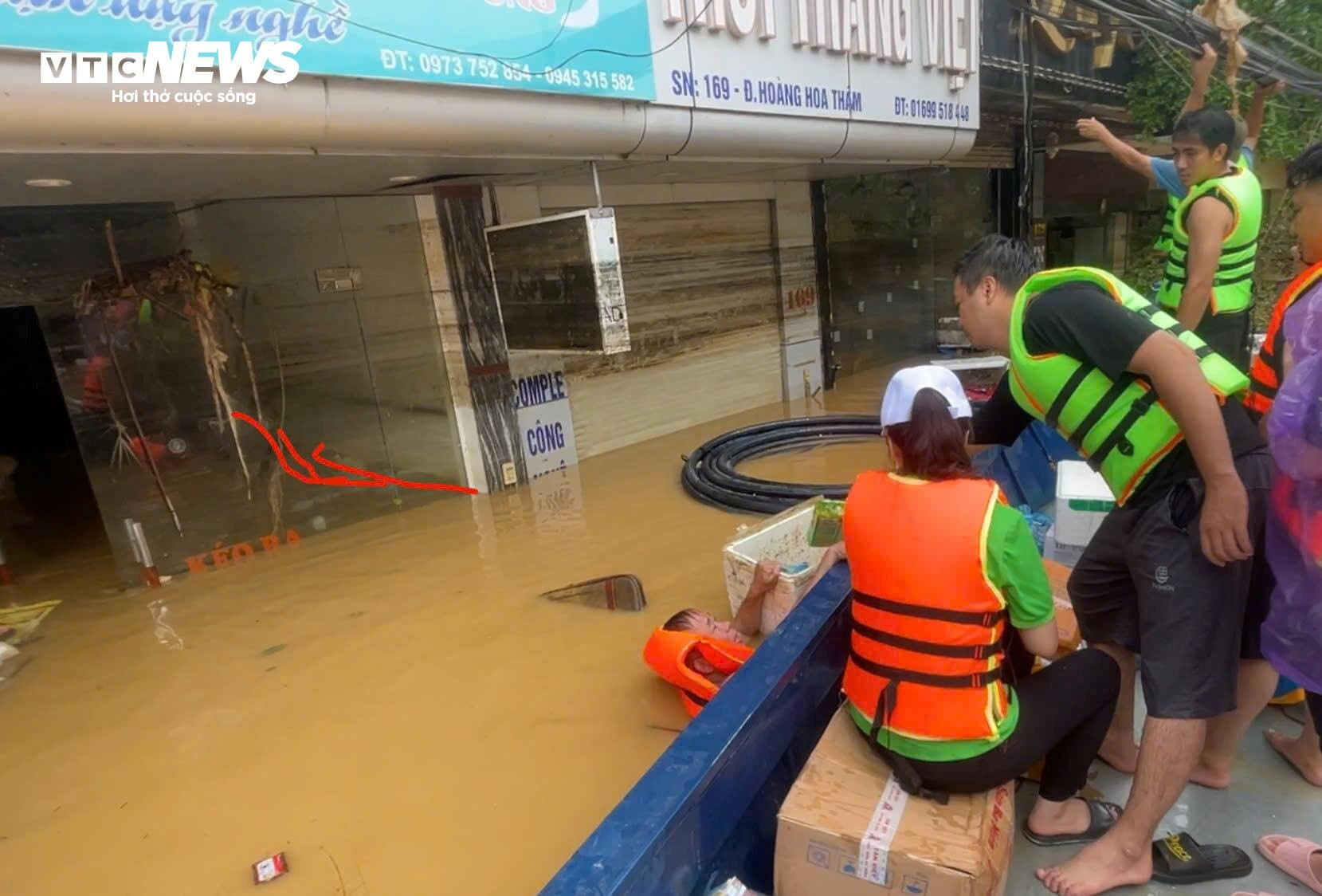 Một người dân trên đường Hoàng Hoa Thám dùng dây buộc ngang người để bơi ra nhận hàng cứu trợ.