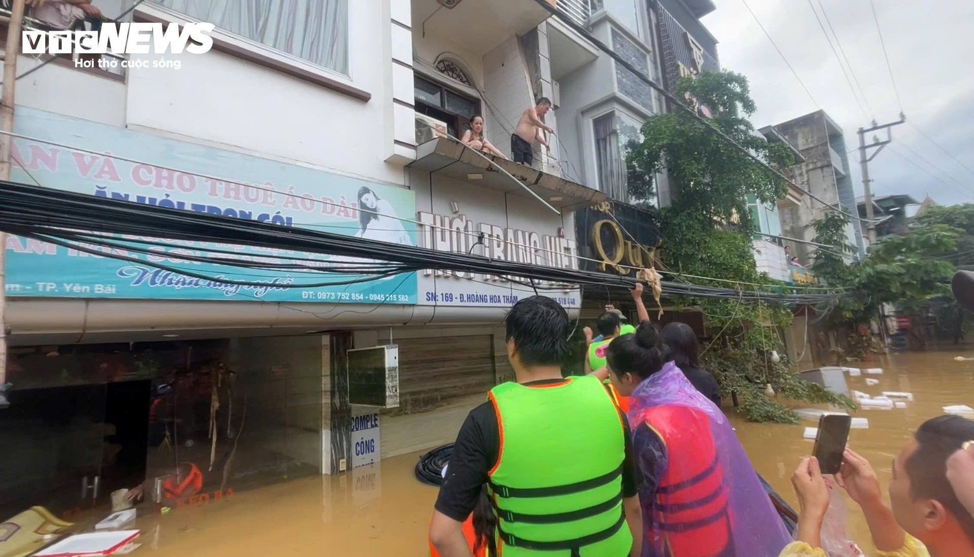 Người dân ngồi trên tầng 2, dùng gậy để lấy thực phẩm từ các đoàn cứu trợ.