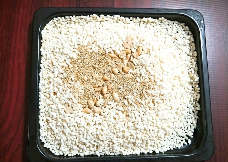 Cho bỏng gạo, lạc, vừng vào khay rồi đưa vào lò nướng. (Ảnh: AFM)