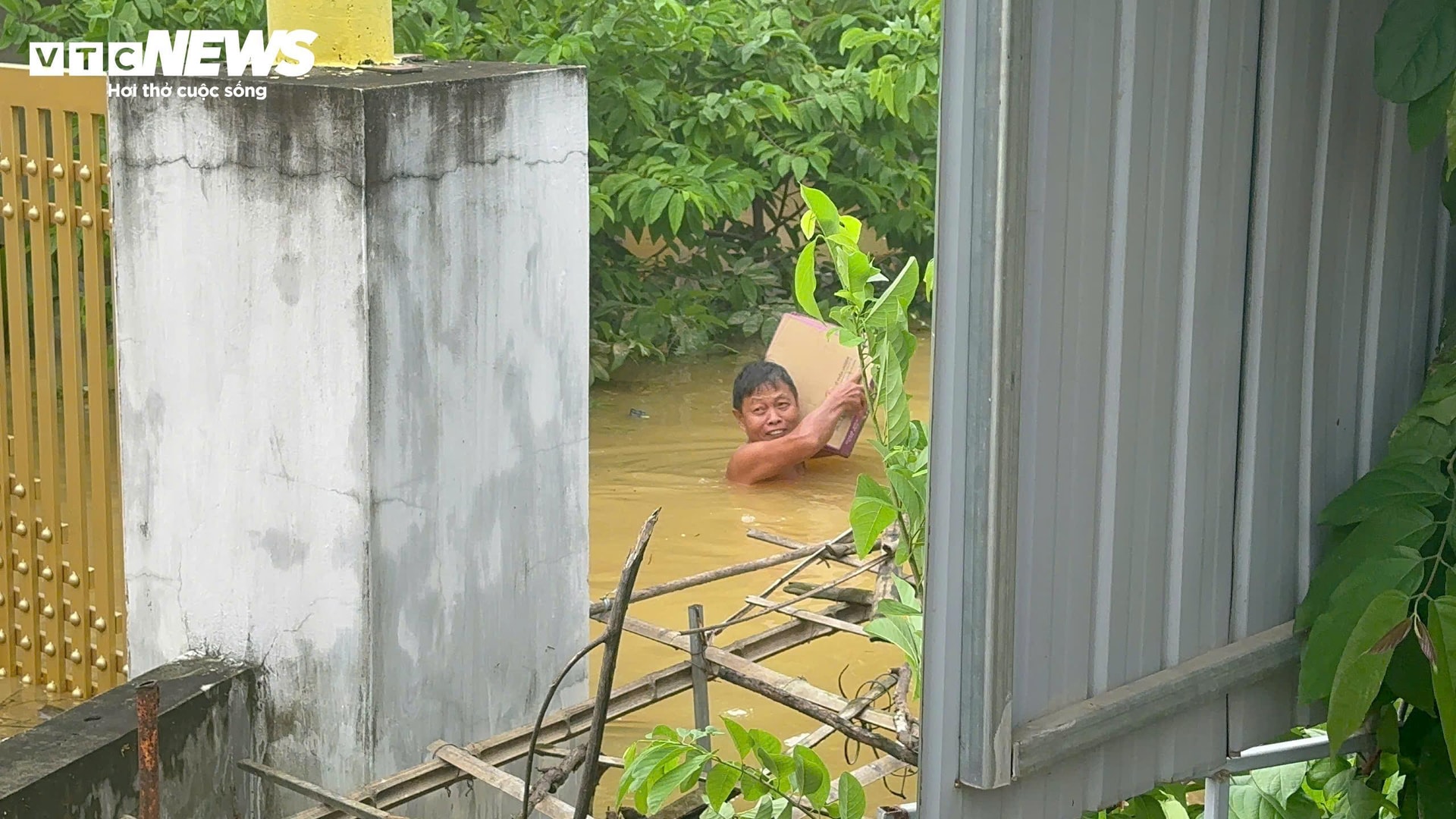 Nước lũ ngập gần đến vai nhưng người đàn ông này vẫn liều mình ra nhận đồ tiếp tế của đoàn từ thiện. (Ảnh: Nguyễn Vương)