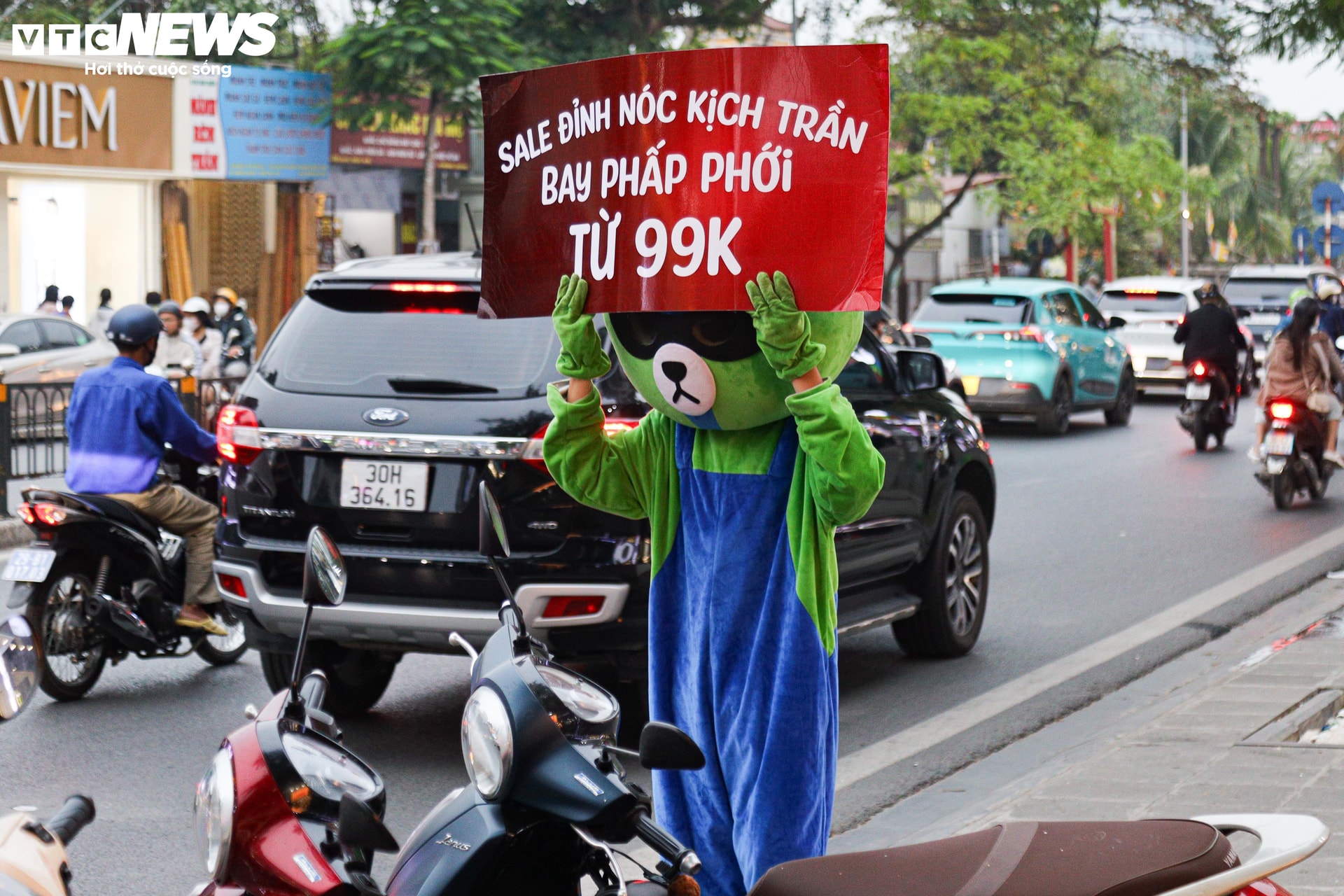 Một cửa hàng thuê người hóa trang thành thú bông (mascot) để trưng biển với slogan 