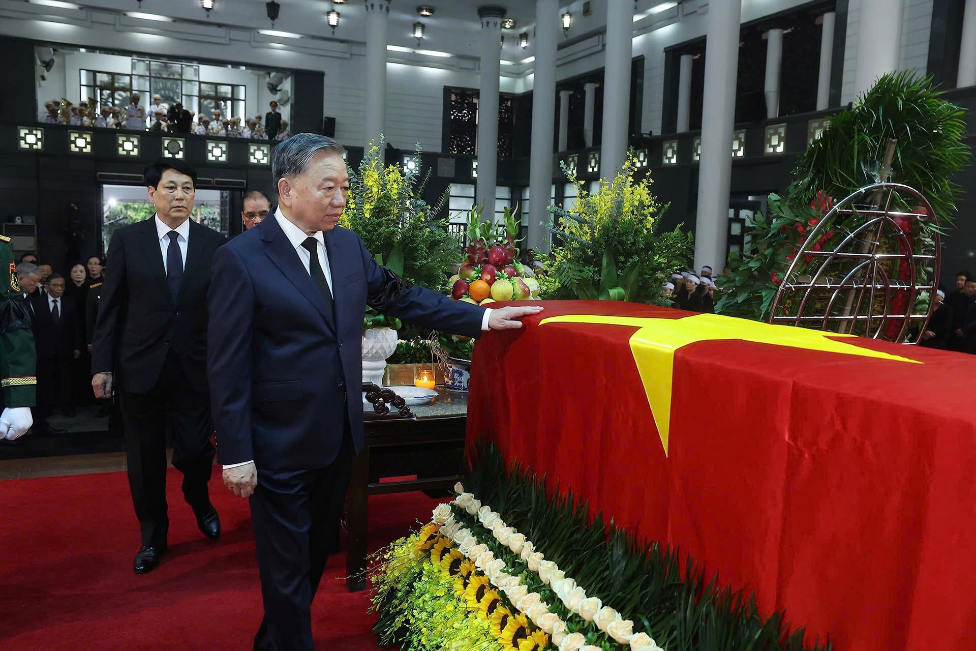 Tổng Bí thư Tô Lâm đặt tay lên linh cữu phủ Quốc kỳ, tiễn biệt nguyên Chủ tịch nước Trần Đức Lương. (Ảnh: TTXVN)