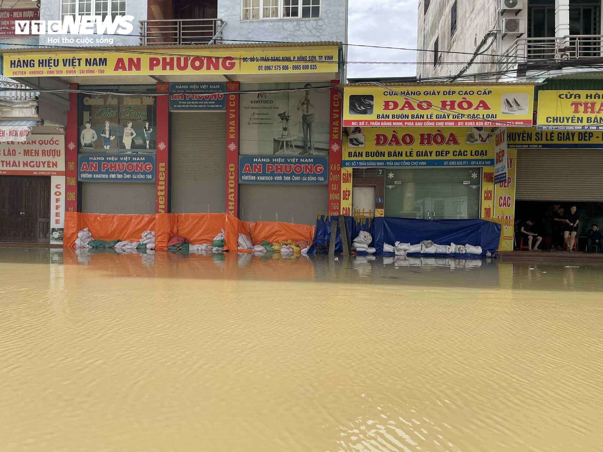 Nhiều tiểu thương dùng bạt, gia cố bao cát để ngăn dòng nước tràn vào cơ sở kinh doanh của mình.