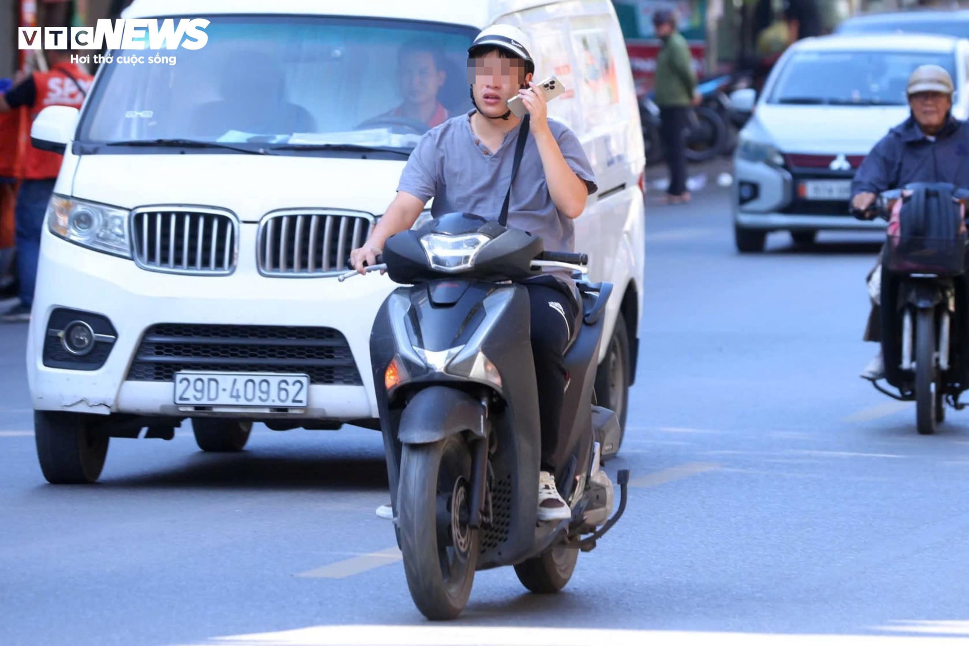 Tài xế dùng điện thoại khi lái xe trên đường.