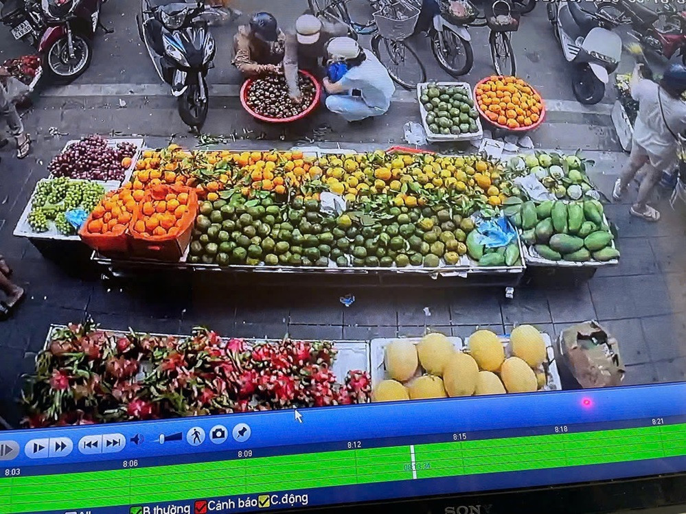 Camera an ninh ghi lại cảnh Nguyễn Thị Oanh tiếp cận quầy hoa quả trước khi thực hiện hành vi trộm cắp chiếc ví của người mua hàng.