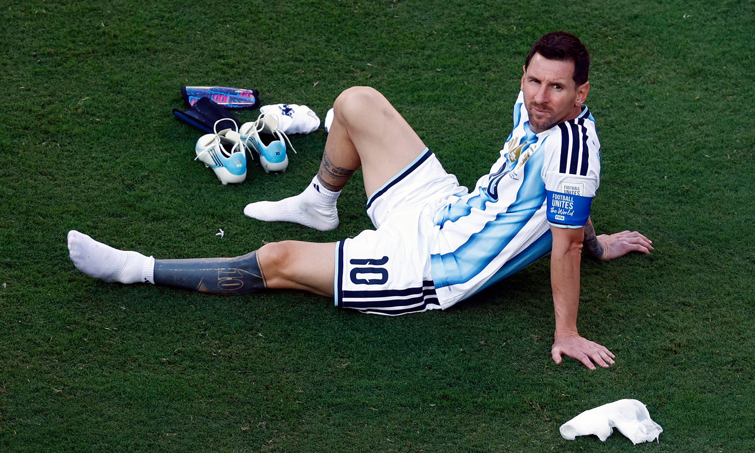 Lionel Messi tháo giày, ngồi xuống sân với vẻ mặt bình thản sau trận thua Tây Ban Nha ở chung kết World Cup 2026. (Ảnh: Reuters)