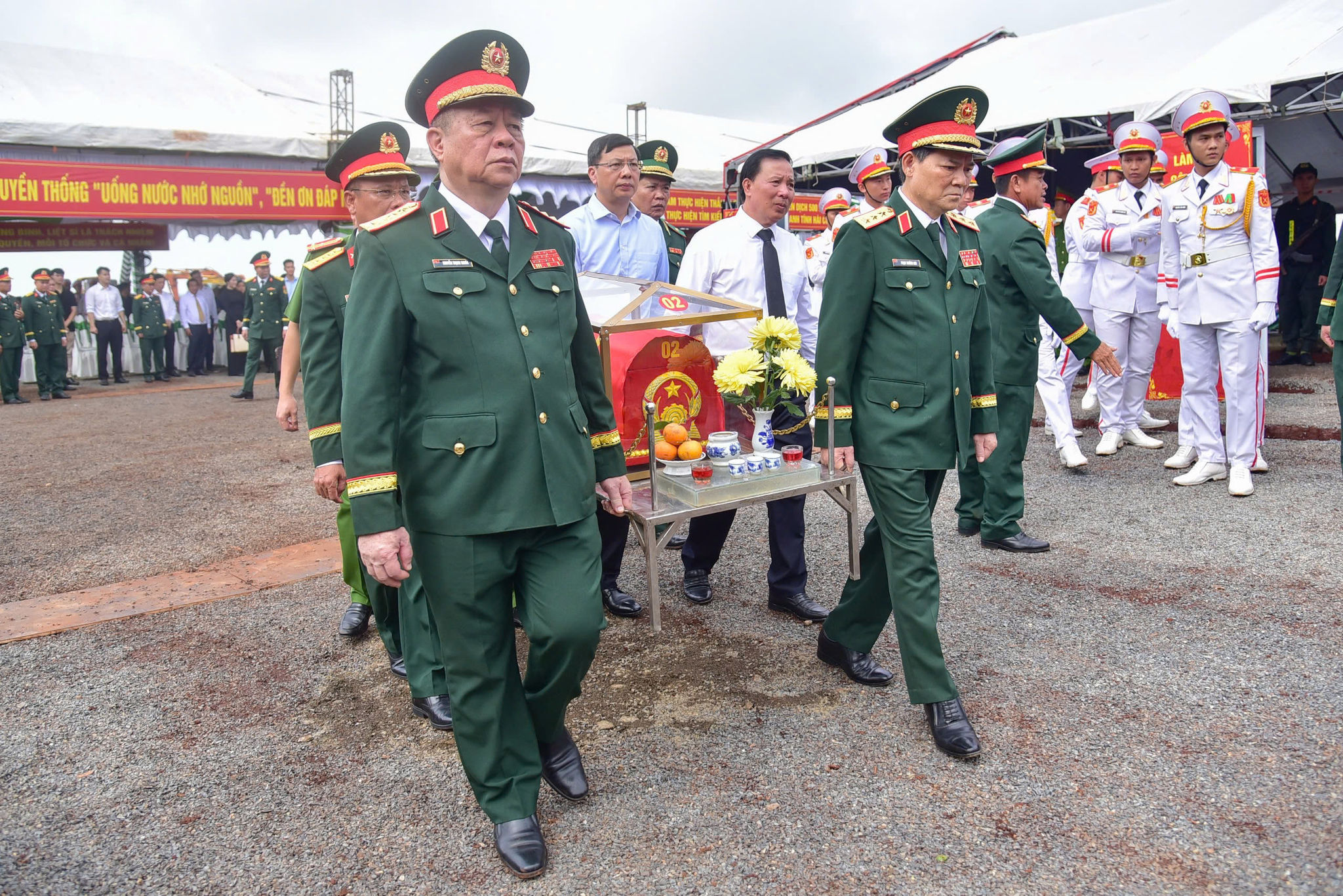 Các đại biểu thực hiện nghi thức di chuyển hài cốt liệt sĩ về nhà quàn để dâng hương. (Ảnh: Lương Ý)