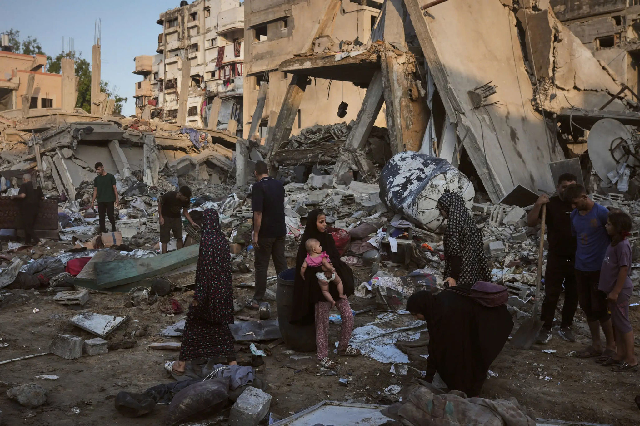 Người dân Palestine thu gom đồ đạc từ đống đổ nát sau cuộc không kích của Israel. (Ảnh: AP)