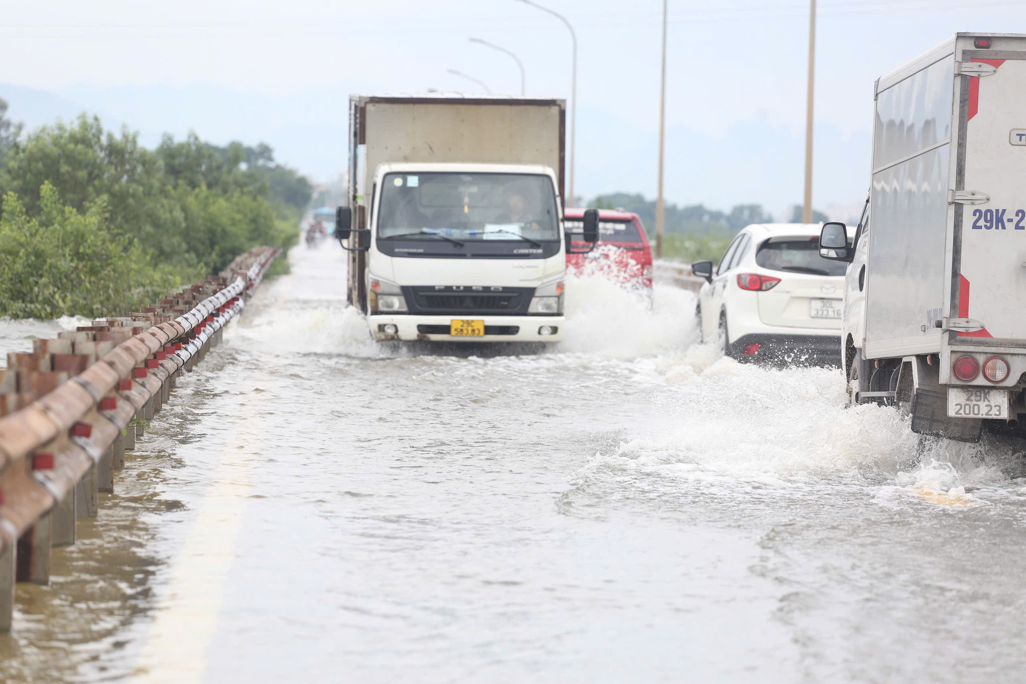 Ô tô đi qua tạo thành sóng nước lớn.