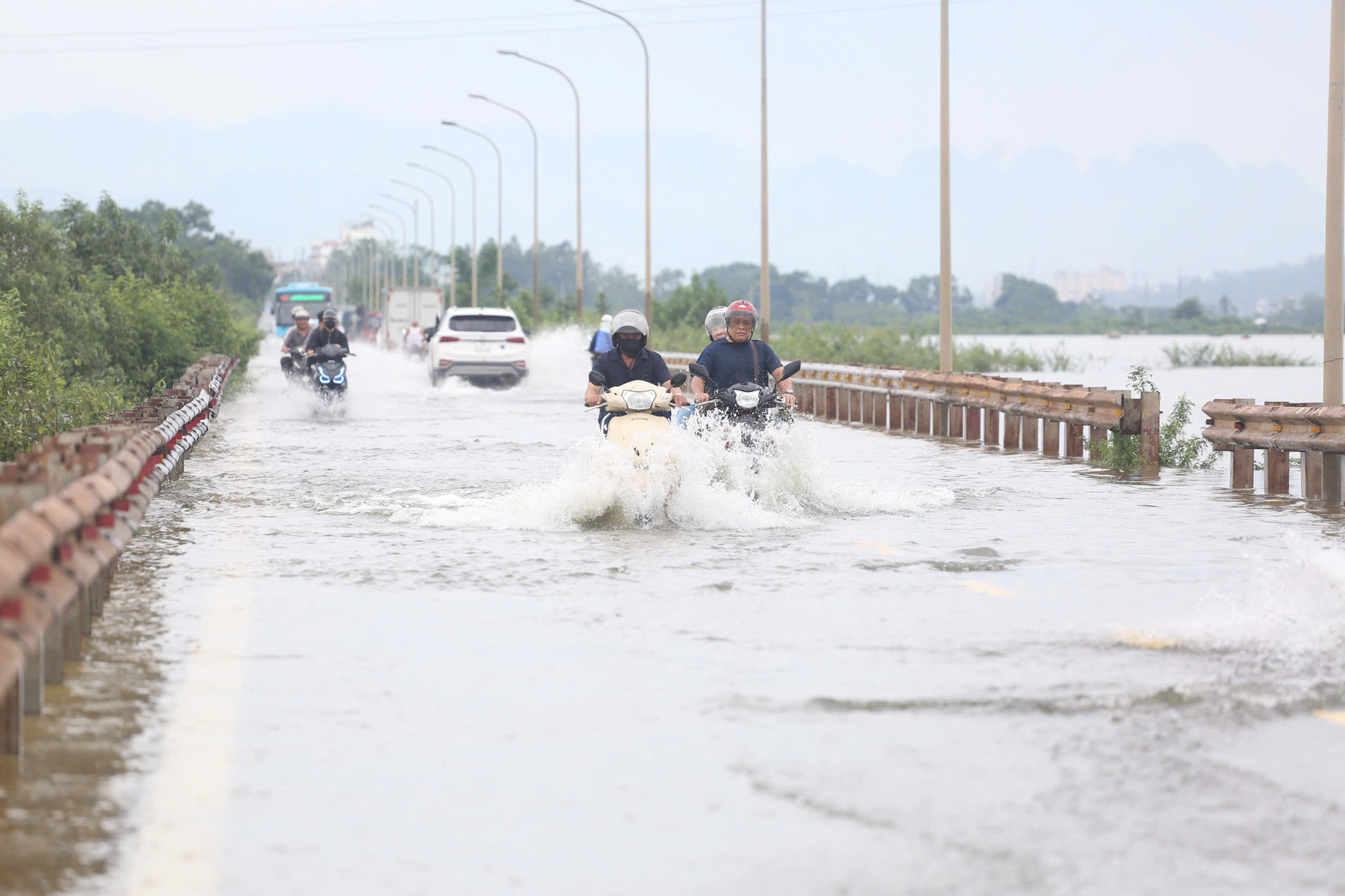 Tại xã Kiều Phú (Hà Nội), tỉnh lộ 421B ngập sâu do nước sông Tích dâng cao, nhiều phương tiện chật vật di chuyển qua vùng ngập.