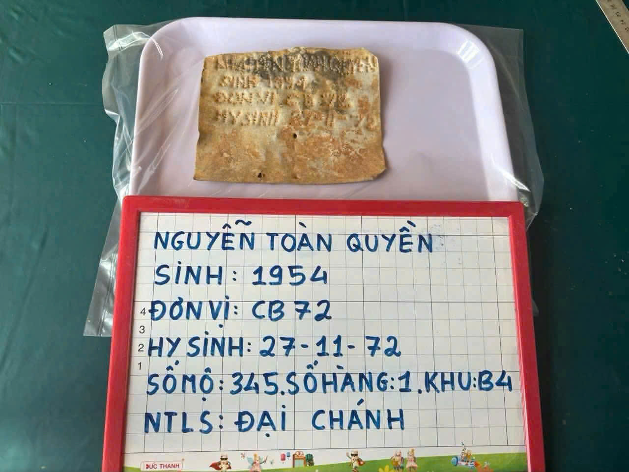 Tấm nhôm được tìm thấy trong phần mộ liệt sĩ. (Ảnh: Quang Cường)