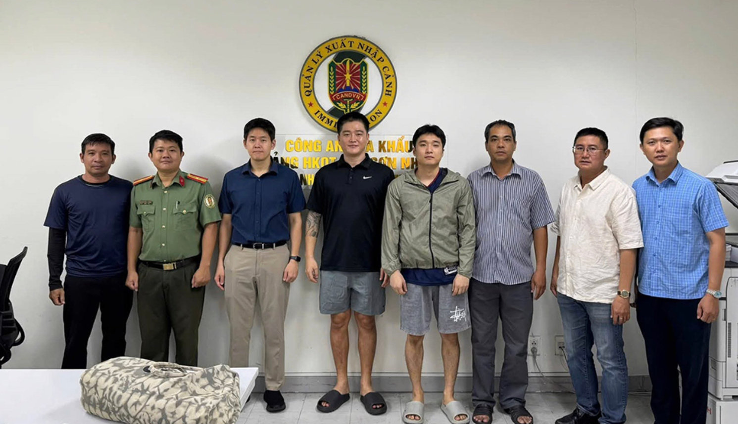 Lực lượng công an bàn giao 2 đối tượng Bang Giseong và Han Joohee cho phía Hàn Quốc (quần cộc, đứng giữa). (Ảnh: CACC)