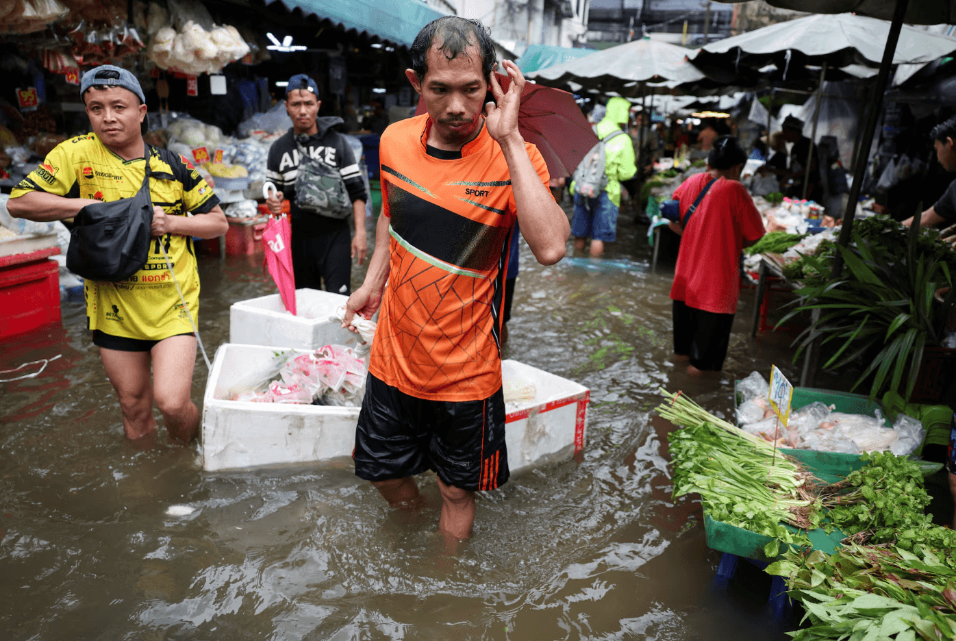Người dân di chuyển qua vùng nước dâng cao tại một khu chợ. (Ảnh: Reuters)